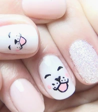 Mãos infantis com unhas decoradas em desenho de cachorro